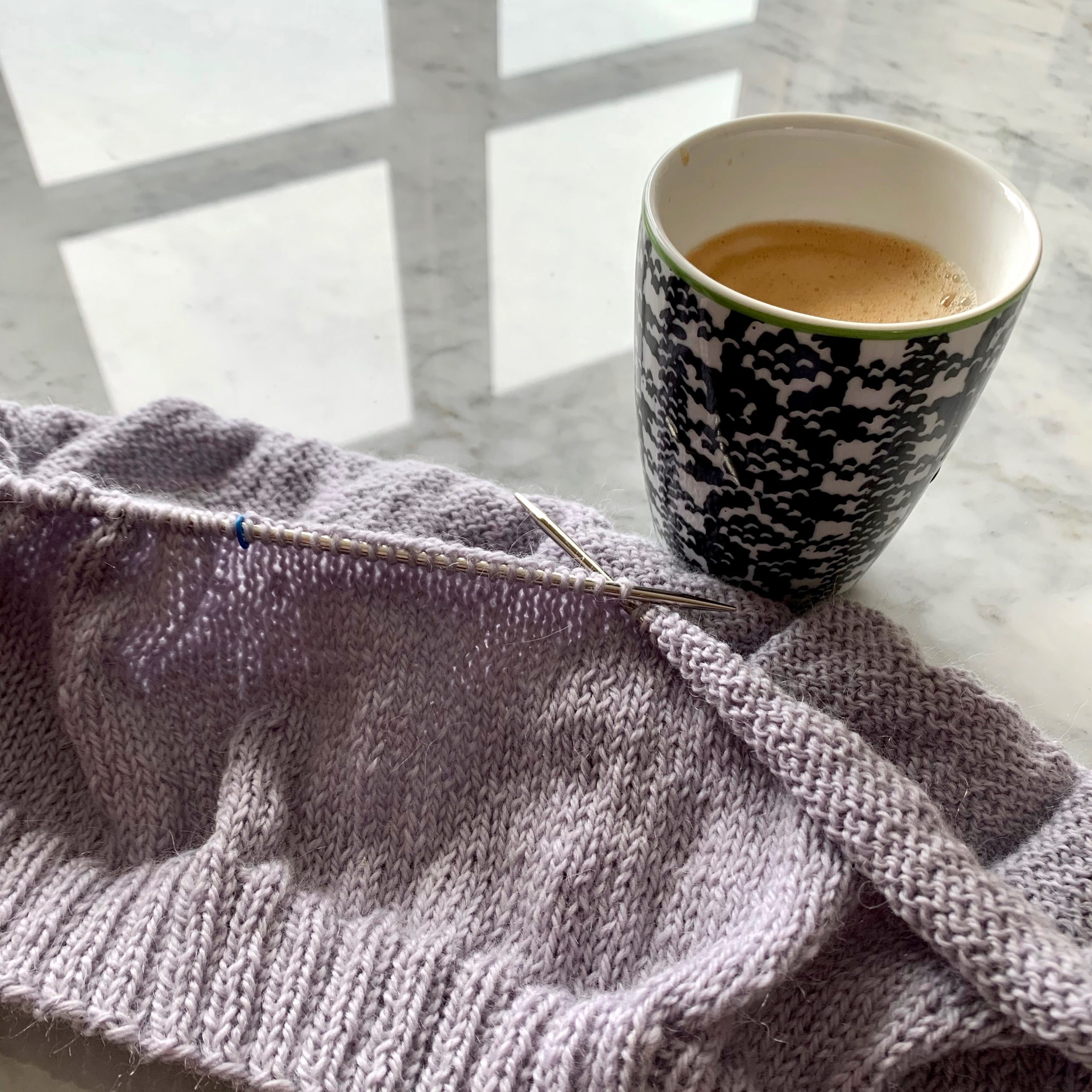Knitters Guild Cup of coffee on a table with knitting in progress