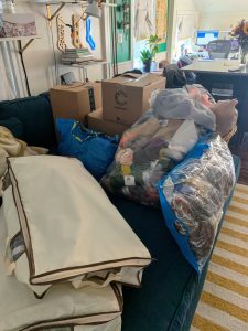 a blue couch covered in bags and boxes full of yarn