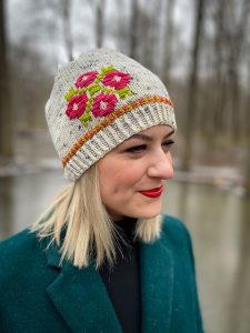 Blond woman wearing a knit hat with rossimine flower details