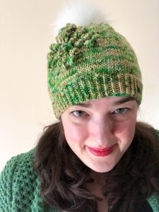 Photo of Tanis Gray wearing a hand knit green hat and sweater