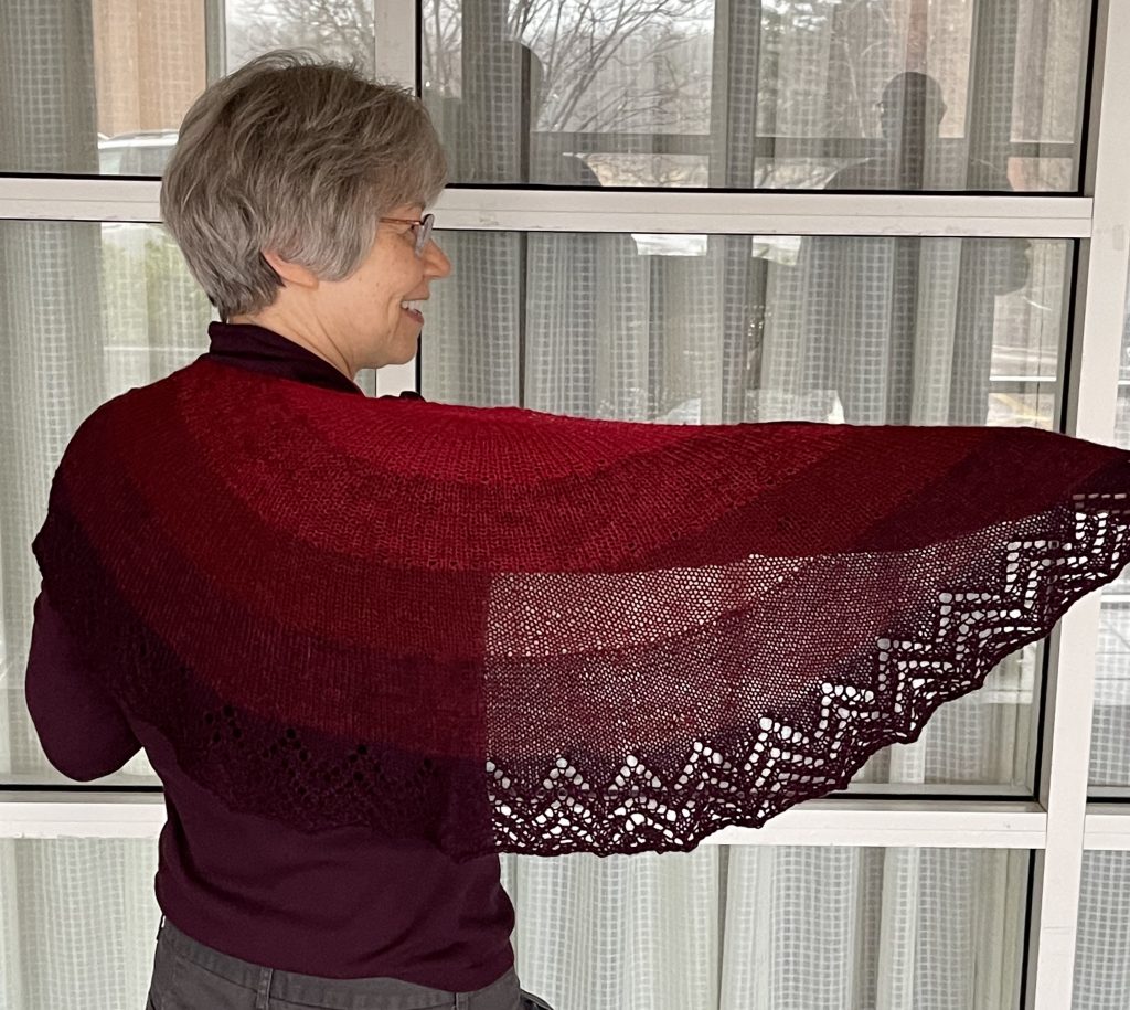 Woman with grey hair showing a red lace shawl