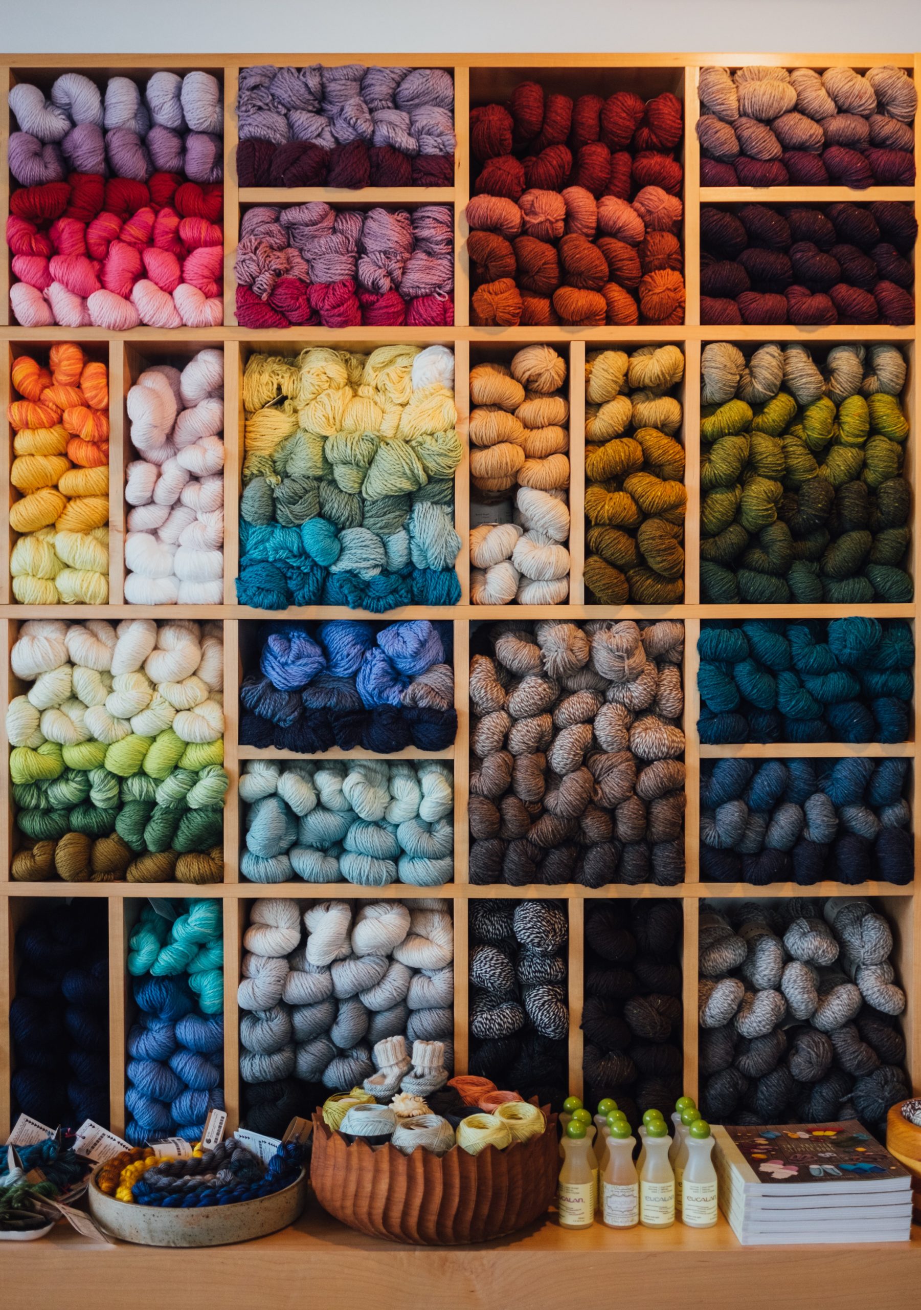 Floor to ceiling yarn of every color sorted into modular shelves.