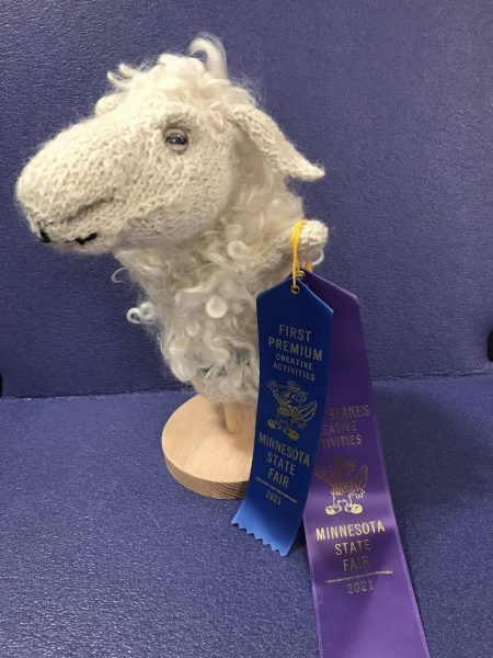 Photo of a hand knit sheep puppet with first premium and sweepstakes ribbons from the Minnesota State Fair