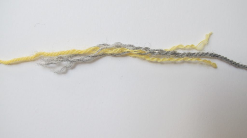Grey and yellow yarn un-plied for splicing