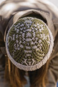 The top of a green and cream hand knit hat