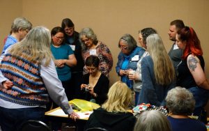 Photo of a group of women around another woman demonstrating knitting