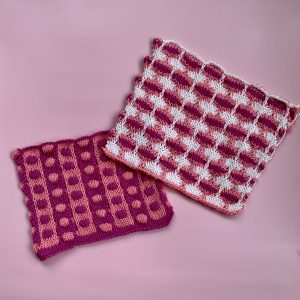 Two handknit swatches of the bubble stitch done in shades of pink, white, and red.