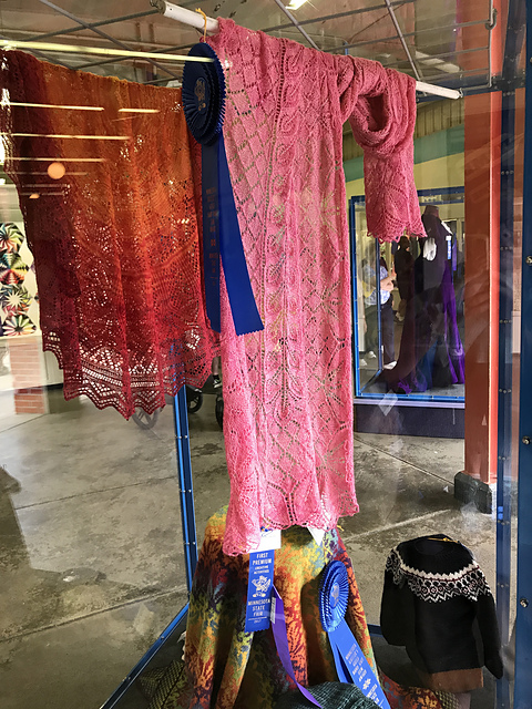 A glass display case of hand knit items at the state fair.