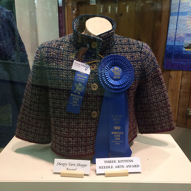 A knit plaid jacket with state fair prize ribbons on it.