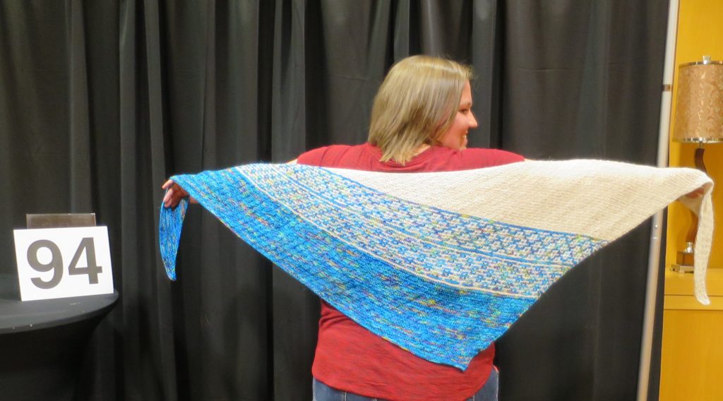 Woman modeling a blue and white hand knit shawl