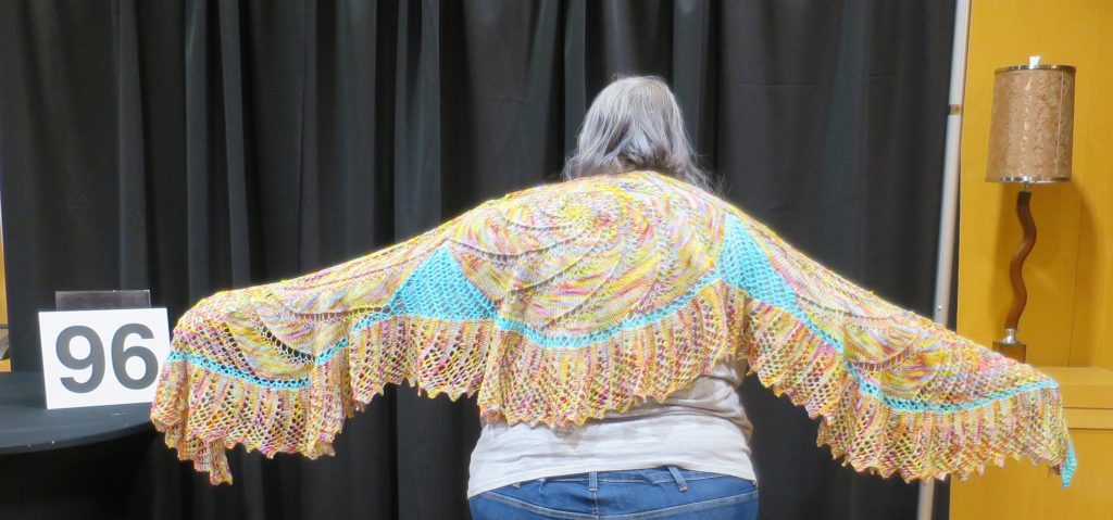 Woman modeling a yellow and teal lace shawl