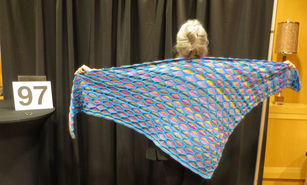 Woman modeling multi-colored shawl in a honeycomb design
