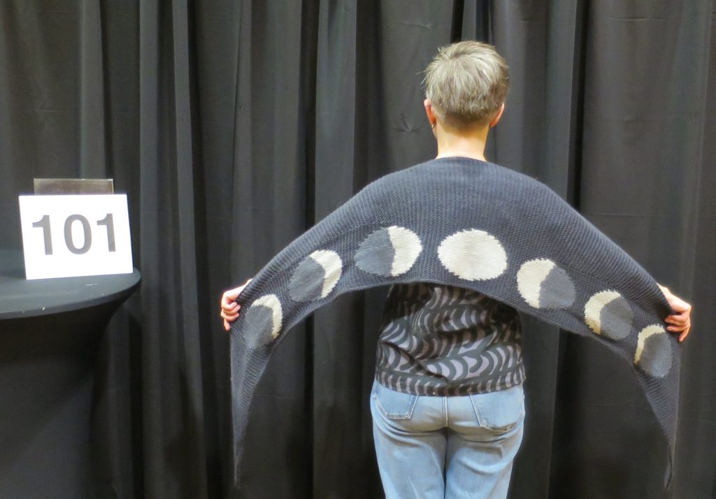 Woman modeling a scarf with the cycles of the moon knit on it
