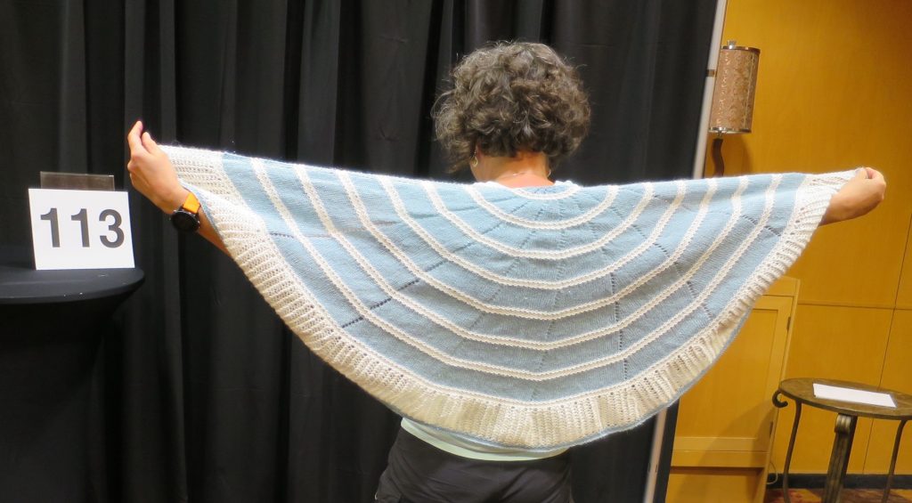 Woman modeling blue and tan hand knit shawl