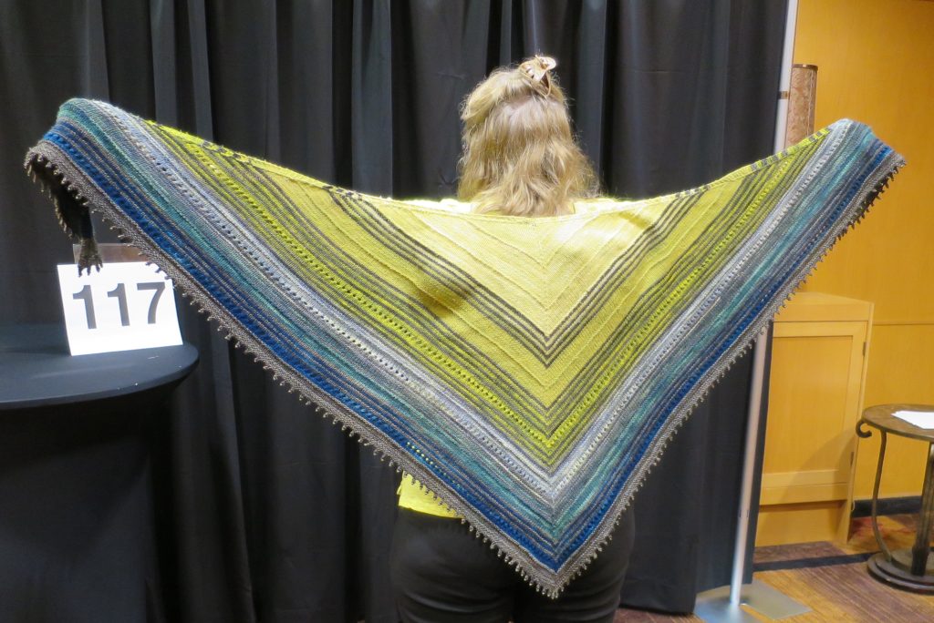 Woman modeling a blue, green and yellow hand knit shawl