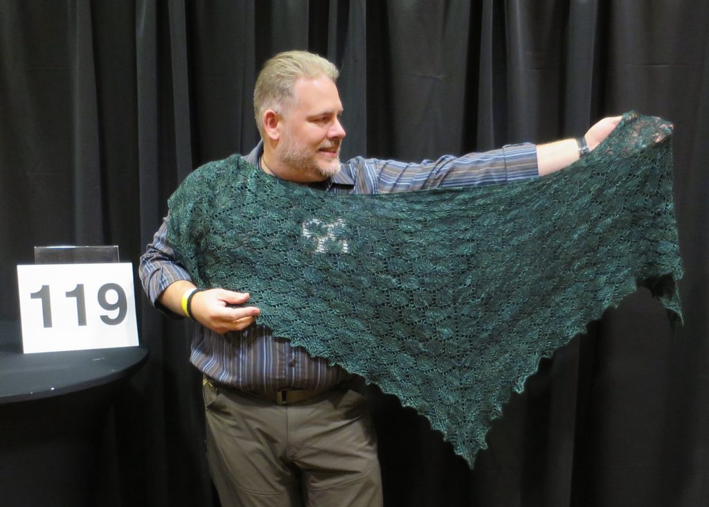 A man modeling a green lace wrap shawl