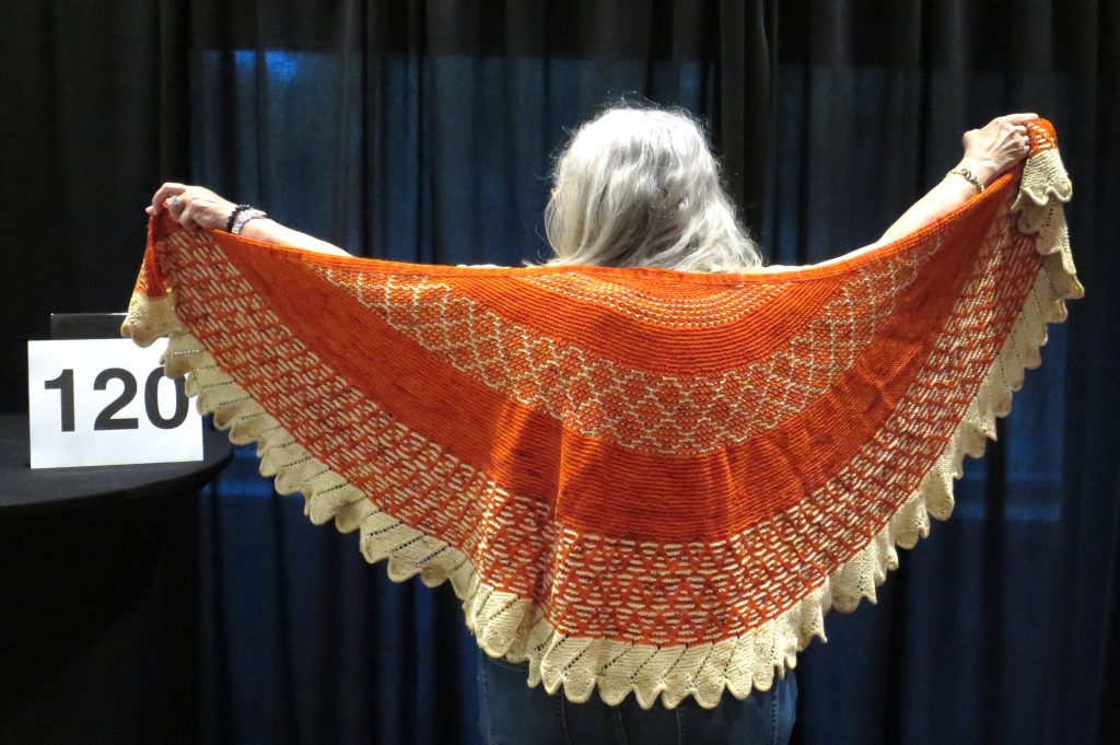 Woman modeling a yellow and orange hand knit shawl