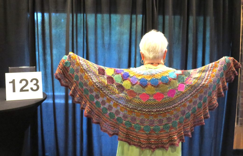 Woman modeling a multi-color hand knit shawl