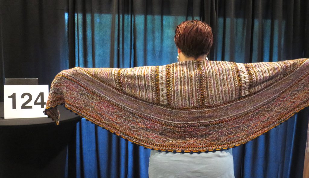Woman models a hadn knit shawl in shades of brown