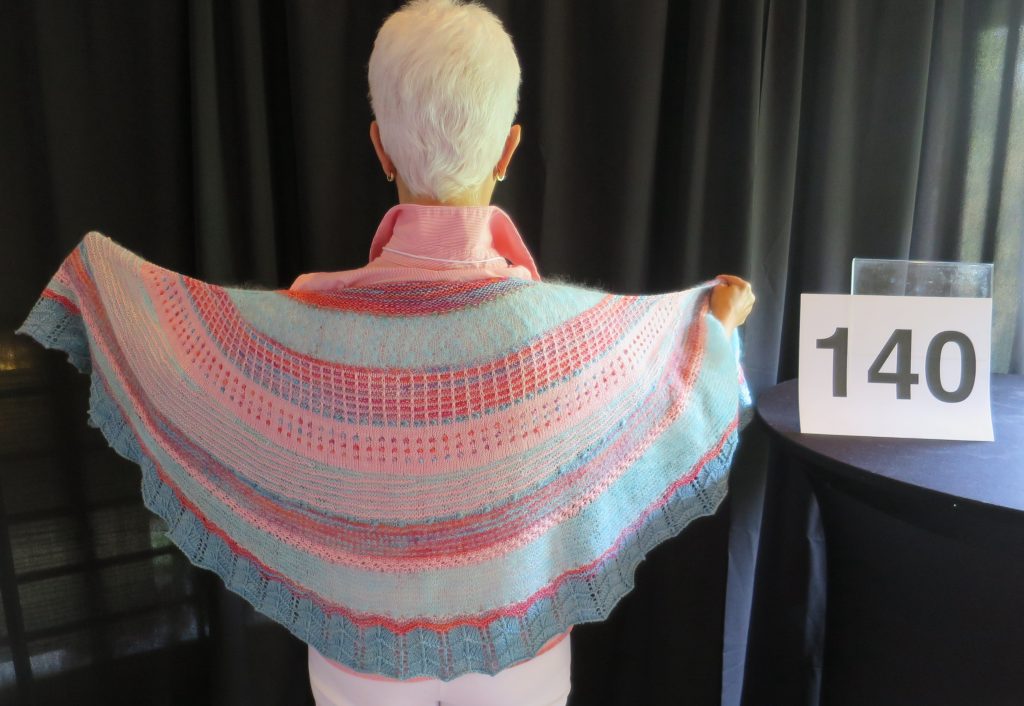 A woman models a multi-color hand knit shawl