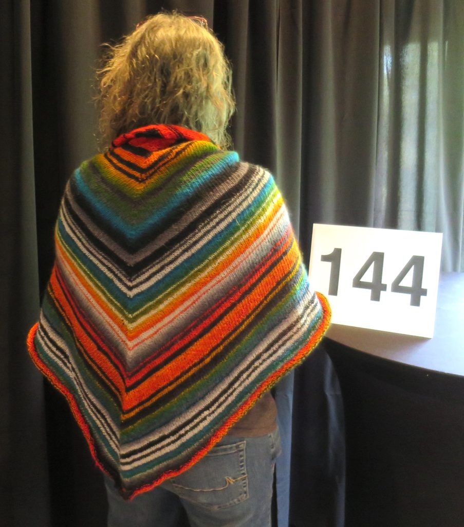 A woman models a mutli-color hand knit shawl