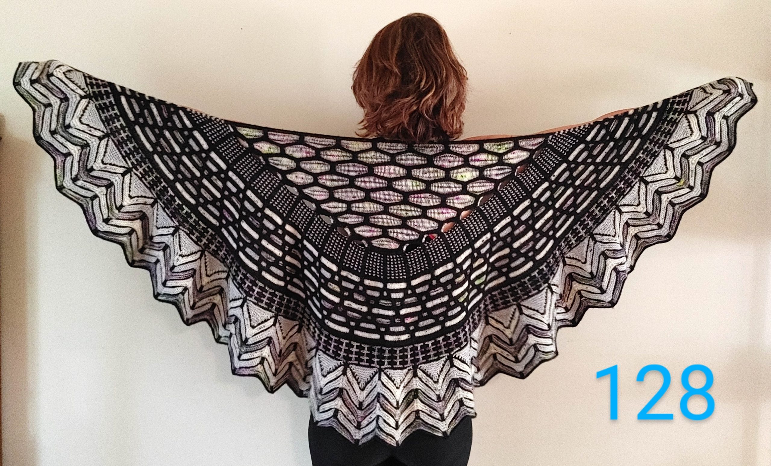 A woman models a black and white hand knit shawl