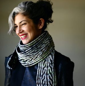 A woman with black and grey hair wears a black and white brioche scarf