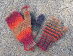 hand knit mittens and fingerless mittens in blue, tan, and orange stripes.