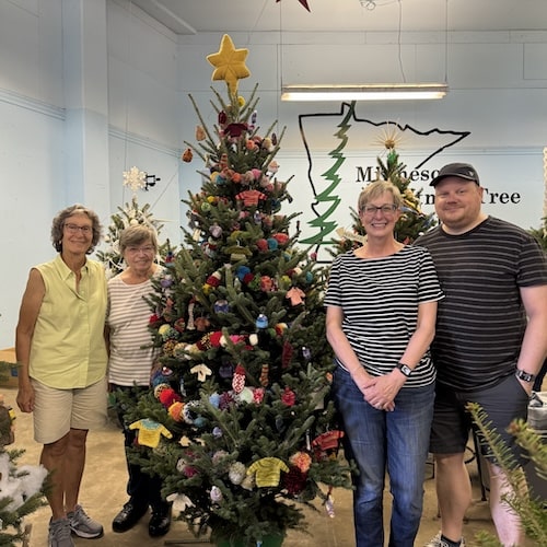 Three women and a mad stand next to a Christmas tree