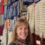 A woman stands in front of a display of Norwegian sweaters