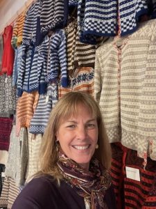 A woman stands in front of a display of Norwegian sweaters